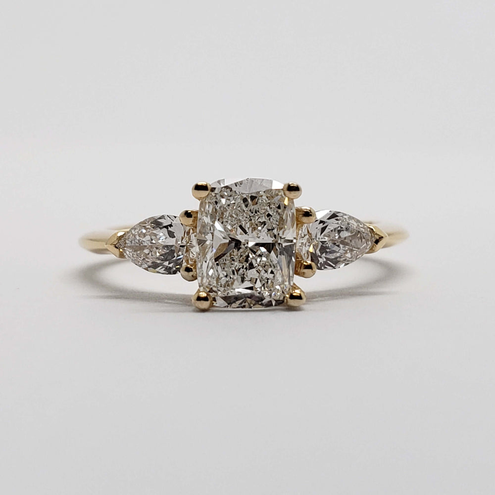 Front view of 14kt yellow gold ring with cushion cut lab diamond and pear side stones