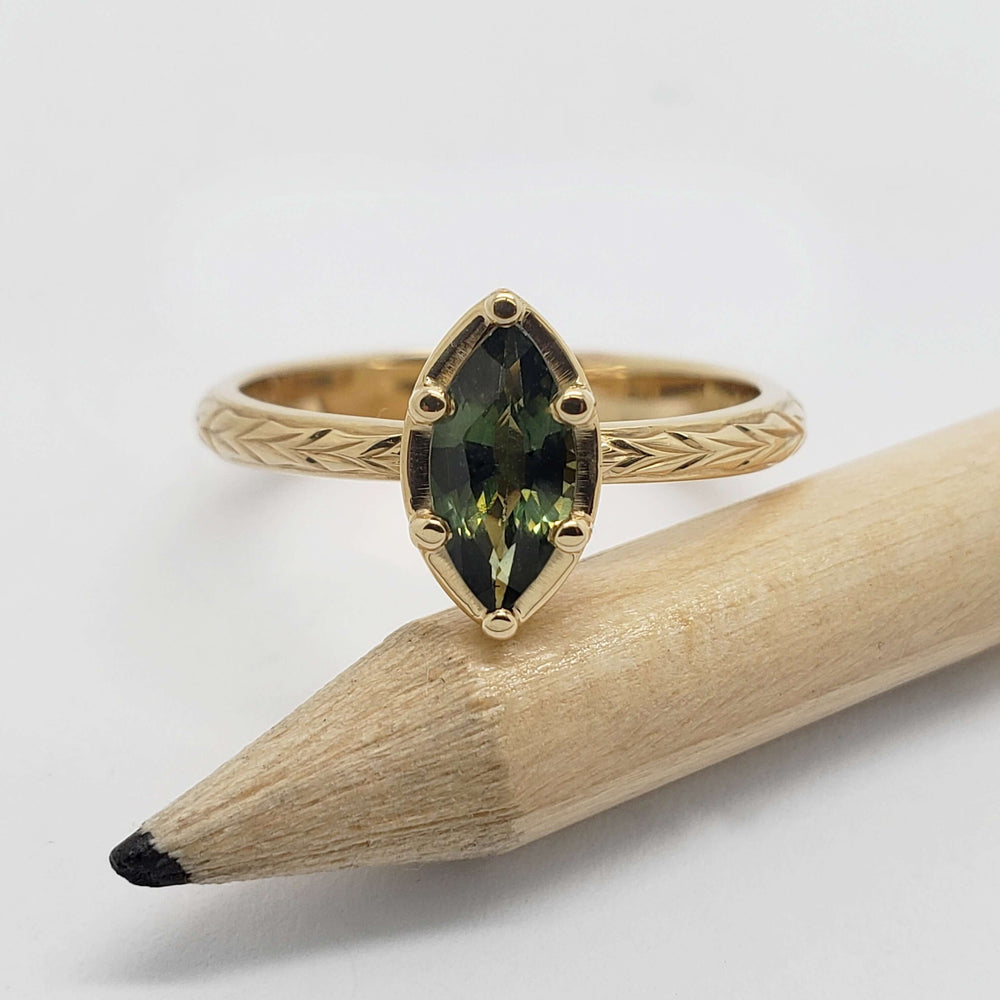 Front view of 14kt yellow gold ring with marquise green sapphire and engraved band