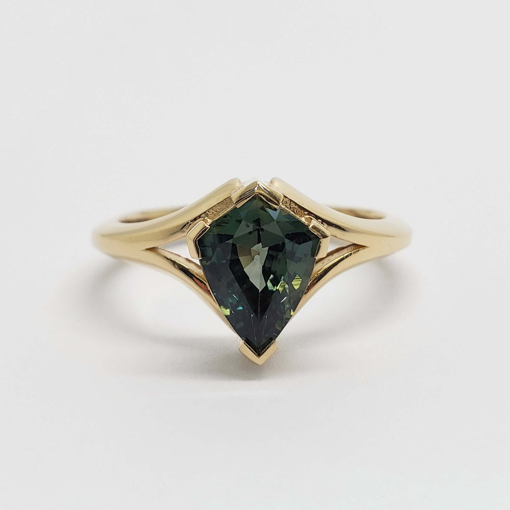 Front view of 14kt yellow gold ring with shield cut teal sapphire in split-shank setting