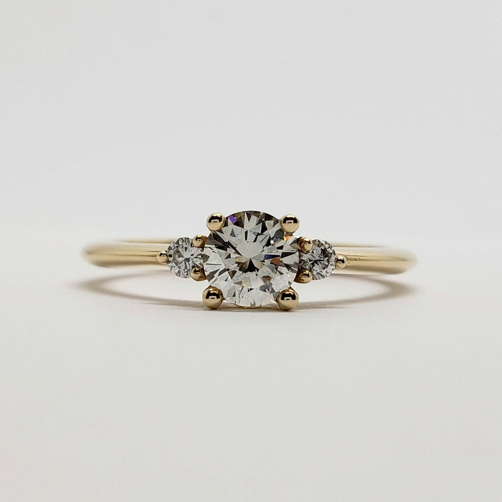 Front view of 14kt yellow gold three-stone diamond engagement ring with round center stone