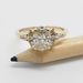 Front view of 14kt yellow gold cluster engagement ring with oval lab diamond beside a pencil
