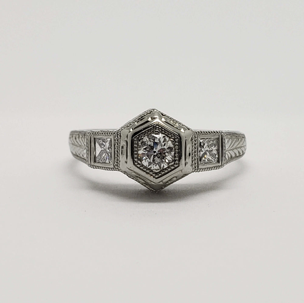 Front view of antique 18kt white gold ring with central round diamond and two princess cut diamonds