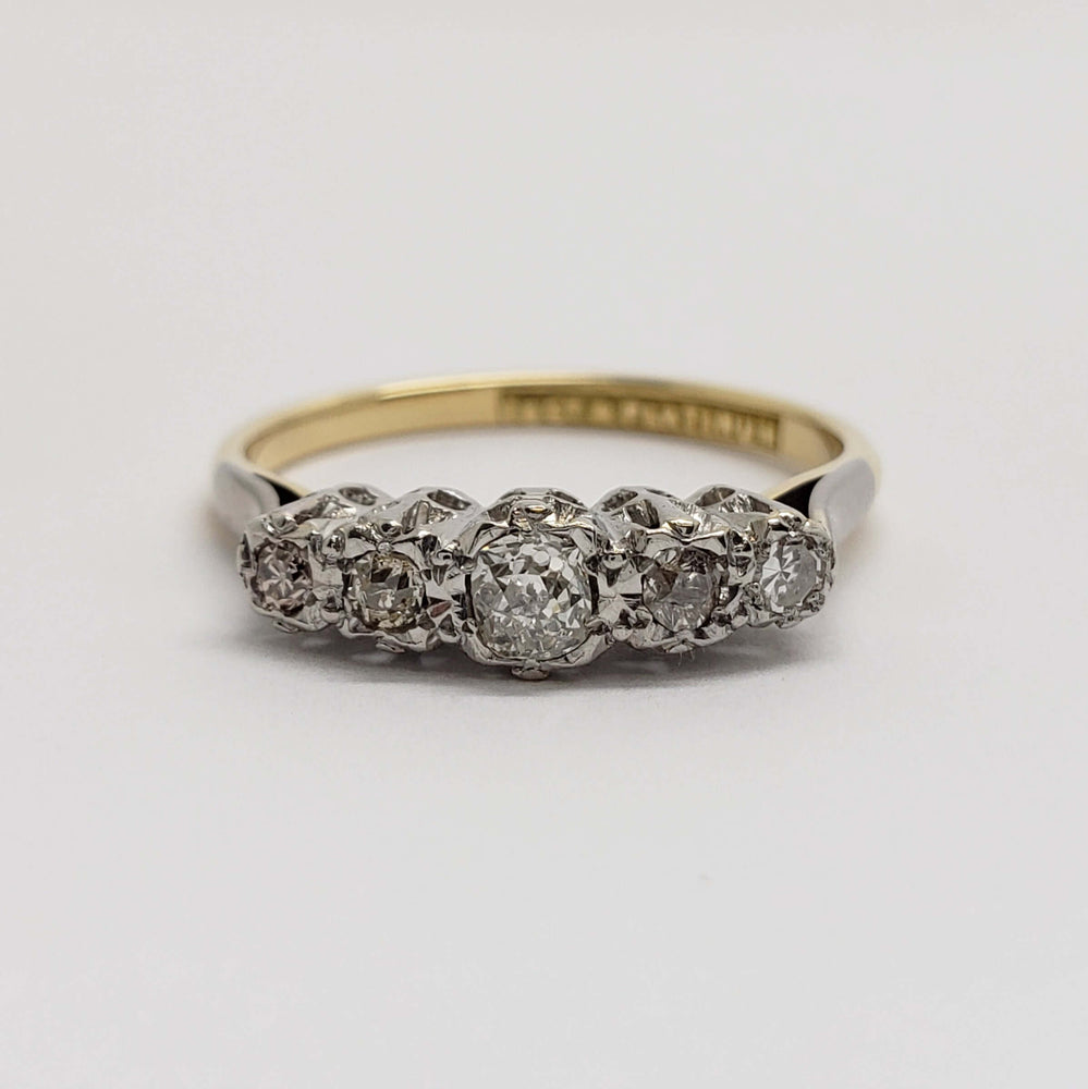 Frontal view of five old-cut diamonds set in platinum atop an 18kt yellow gold band