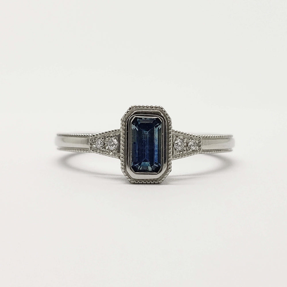Front view of emerald cut blue Montana sapphire ring in white gold with diamond accents