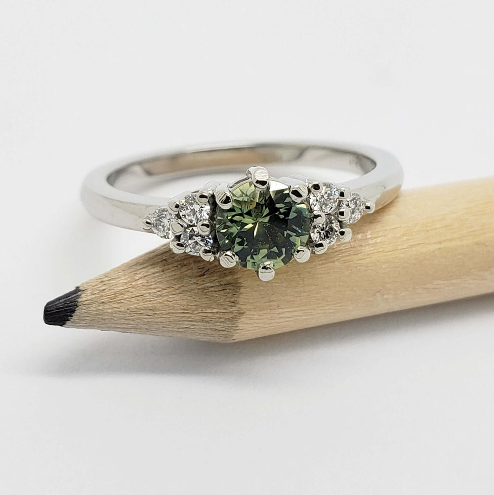 Front view of green Australian sapphire and diamond ring in white gold, beside a pencil