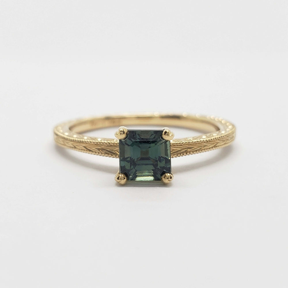Front view of 14kt yellow gold ring with green asscher cut sapphire and engraved details
