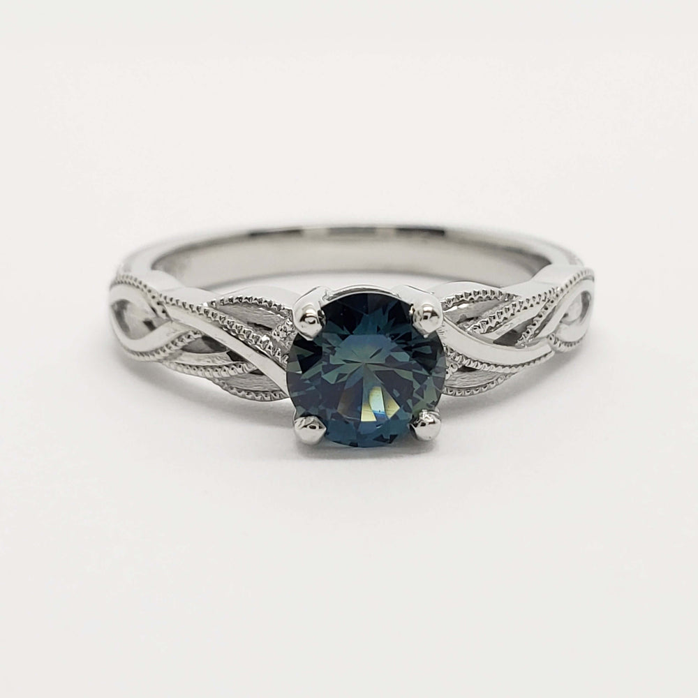 Front view of 14kt white gold ring featuring a blue Montana sapphire and intricate interlace design