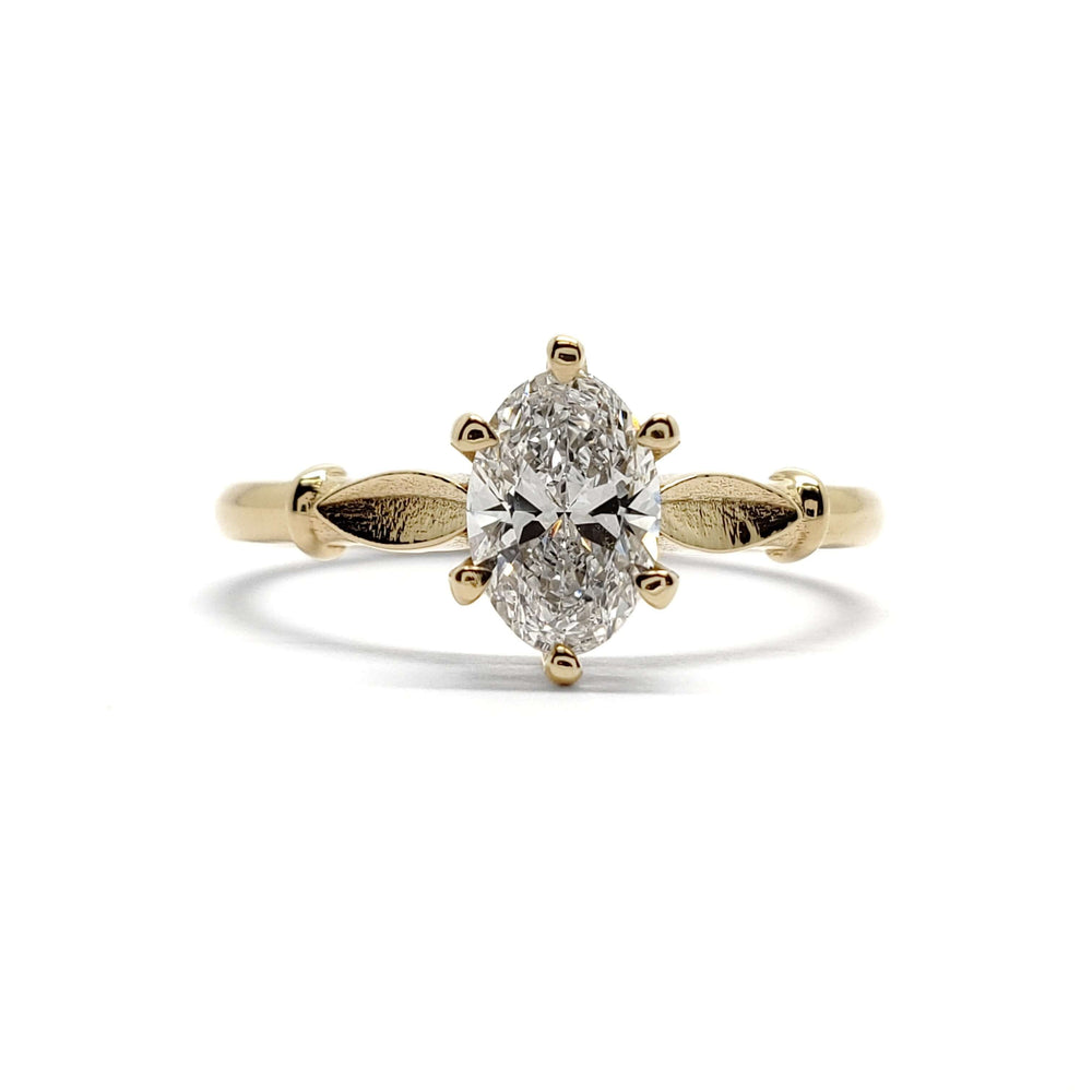 Front view of handcrafted yellow gold ring with oval lab diamond and leaf accents