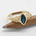 Front view of marquise blue Montana sapphire ring in yellow gold with textured leafy details