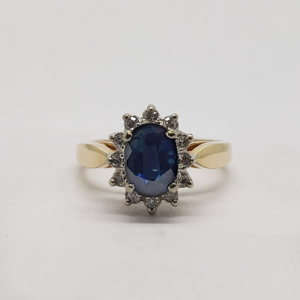 Front view of sapphire halo ring with diamond accents in yellow and white gold