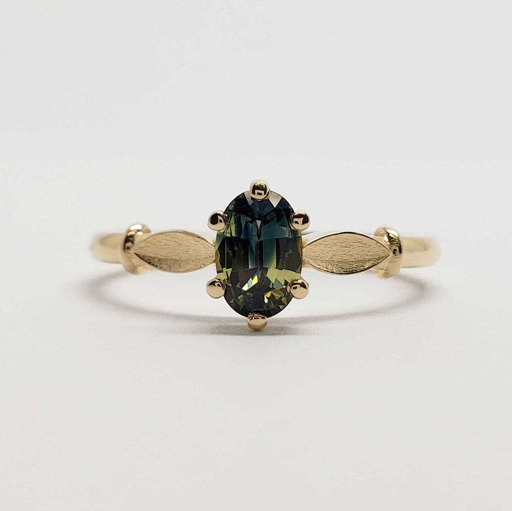 Front view of 14kt yellow gold ring with oval blue-green Australian sapphire and leaf accents