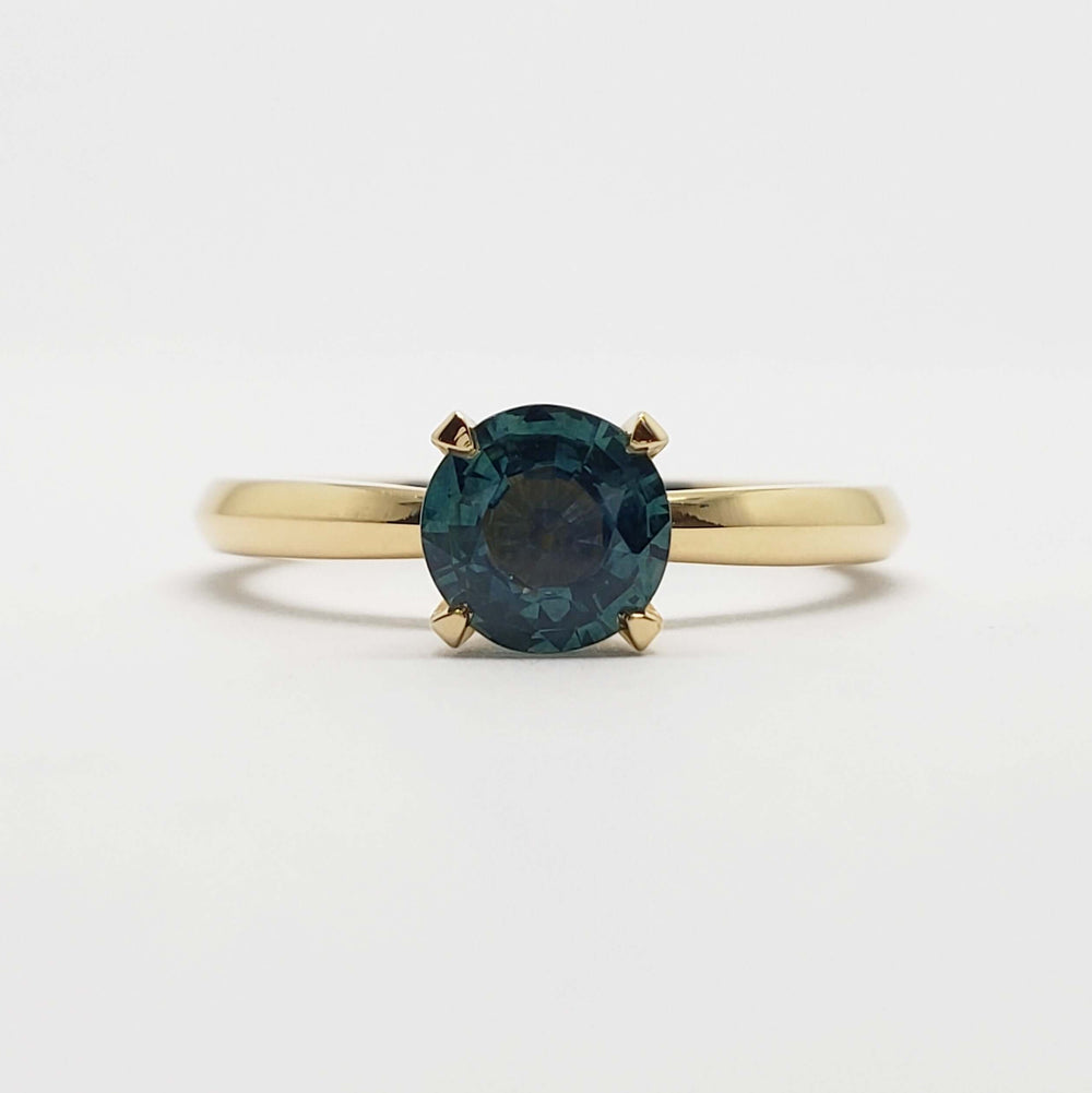 Front view of yellow gold ring with round teal Montana sapphire