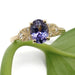 Front view of 14kt yellow gold ring with oval sapphire and diamond details on a leaf