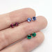 Three pairs of gemstone stud earrings in 14kt gold, including tanzanite, on a hand