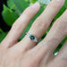 Green Australian sapphire and diamond engagement ring in white gold, shown on hand