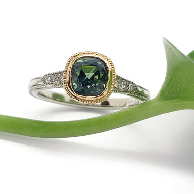 Green Madagascar sapphire engagement ring in 14k gold with diamond accents, shown with a leaf