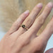 Green sapphire and yellow gold floral engagement ring shown on a hand
