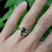 Green sapphire engagement ring in yellow gold stacked with chevron bands on hand