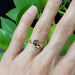 Green sapphire engagement ring stacked with a leaf motif band on a hand