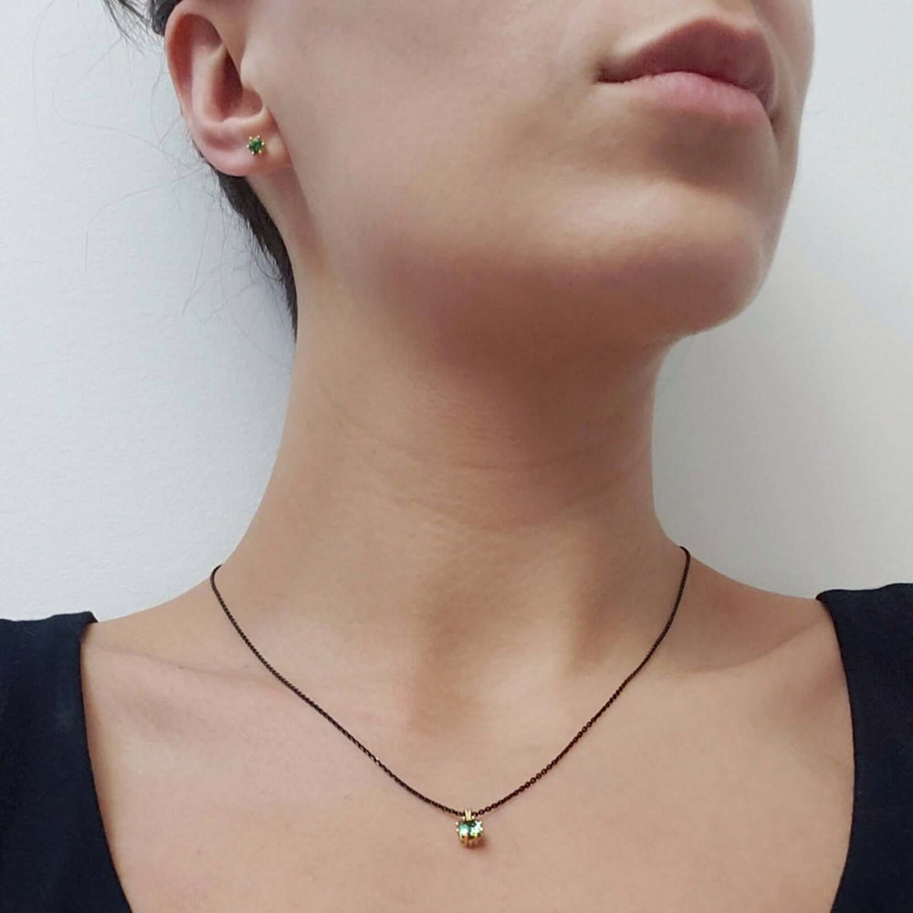Model wearing 14kt yellow gold green tourmaline stud earrings and pendant necklace