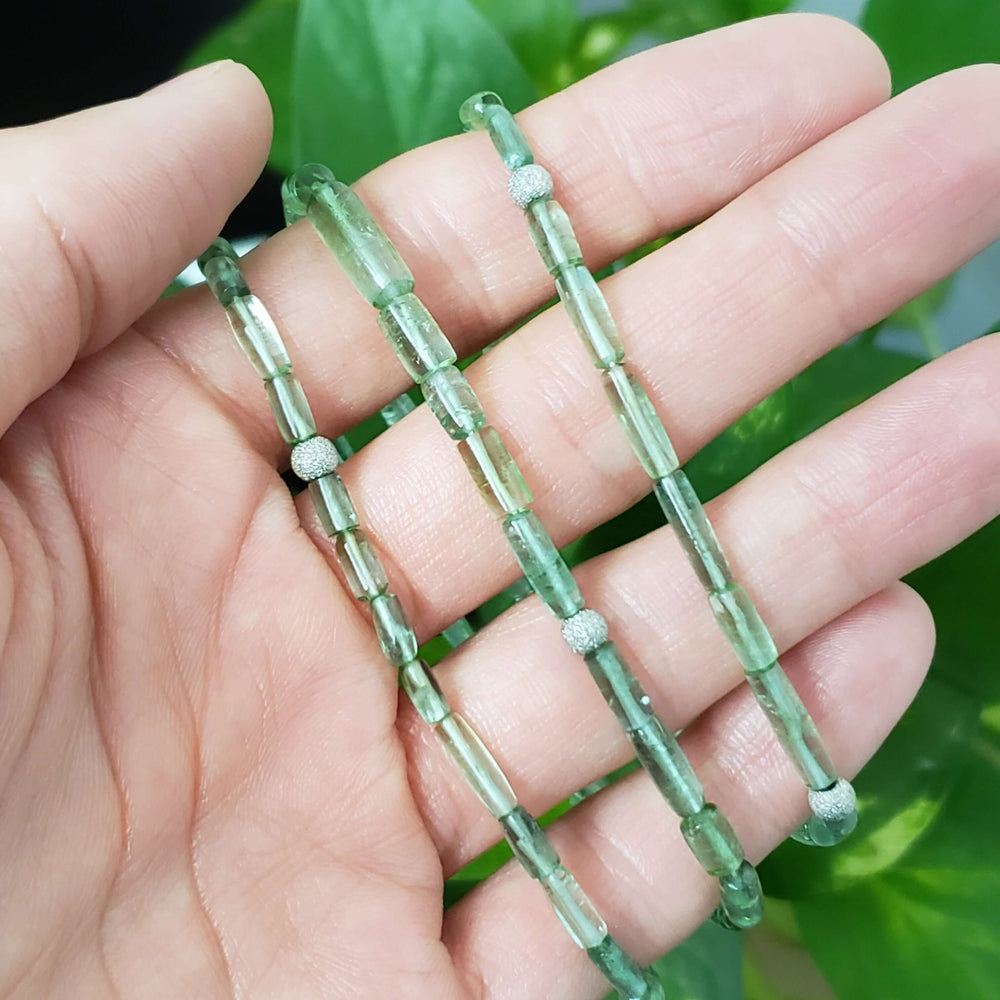 Green tourmaline and white gold bead necklace draped across a hand