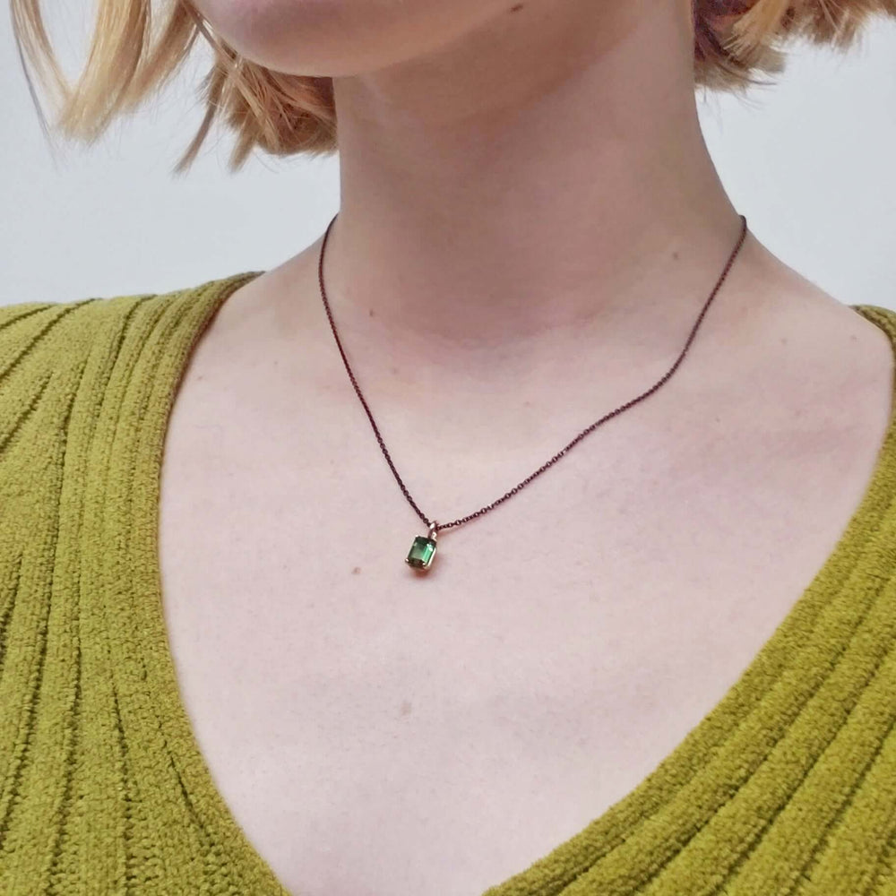 Green tourmaline pendant necklace worn on model with green sweater