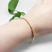 Single hammered 14kt yellow gold bangle worn on wrist with green leaves