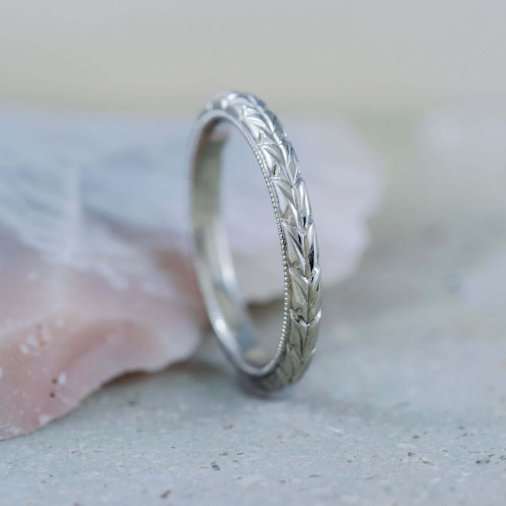 Hand-engraved 14kt white gold wheat wedding band with millgrain, upright on stone