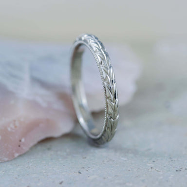 Hand-engraved 14kt white gold wheat wedding band with millgrain, upright on stone