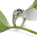 Hand-engraved white gold Montana sapphire and diamond ring beside a green leaf