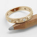 Hand-engraved yellow gold wedding ring with flush-set diamonds resting on pencil