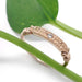 Hand engraved 14kt rose gold wedding ring with lab diamond, shown with green leaves