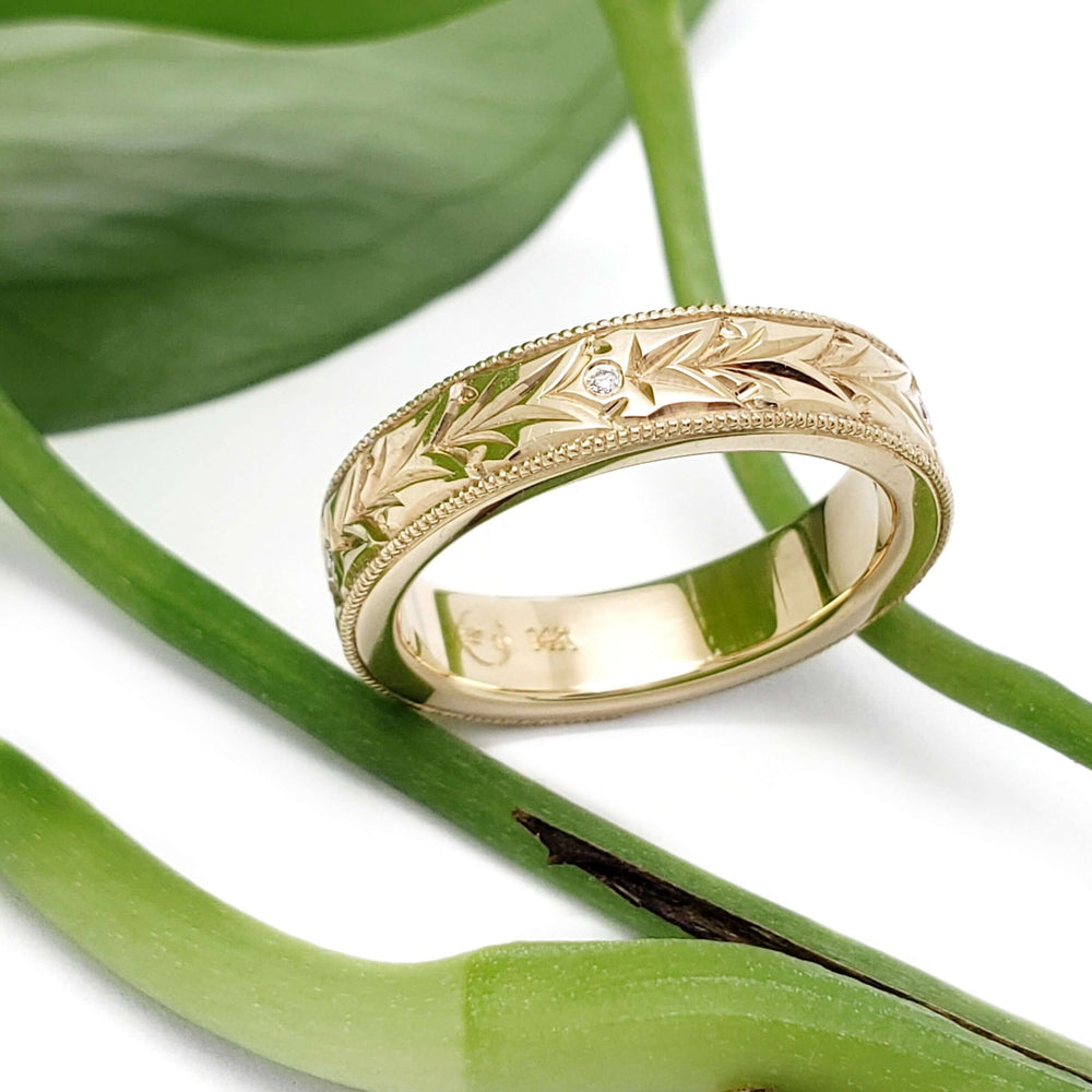 Hand engraved 14kt yellow gold wedding ring with Canadian diamonds, on green leaves