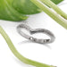 Hand engraved 14kt white gold chevron wedding ring beside green leaves