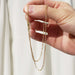 Hand holding 10kt yellow gold flat cable link chain in natural light