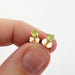 Hand holding 14kt yellow gold peridot stud earrings in a 4-claw setting