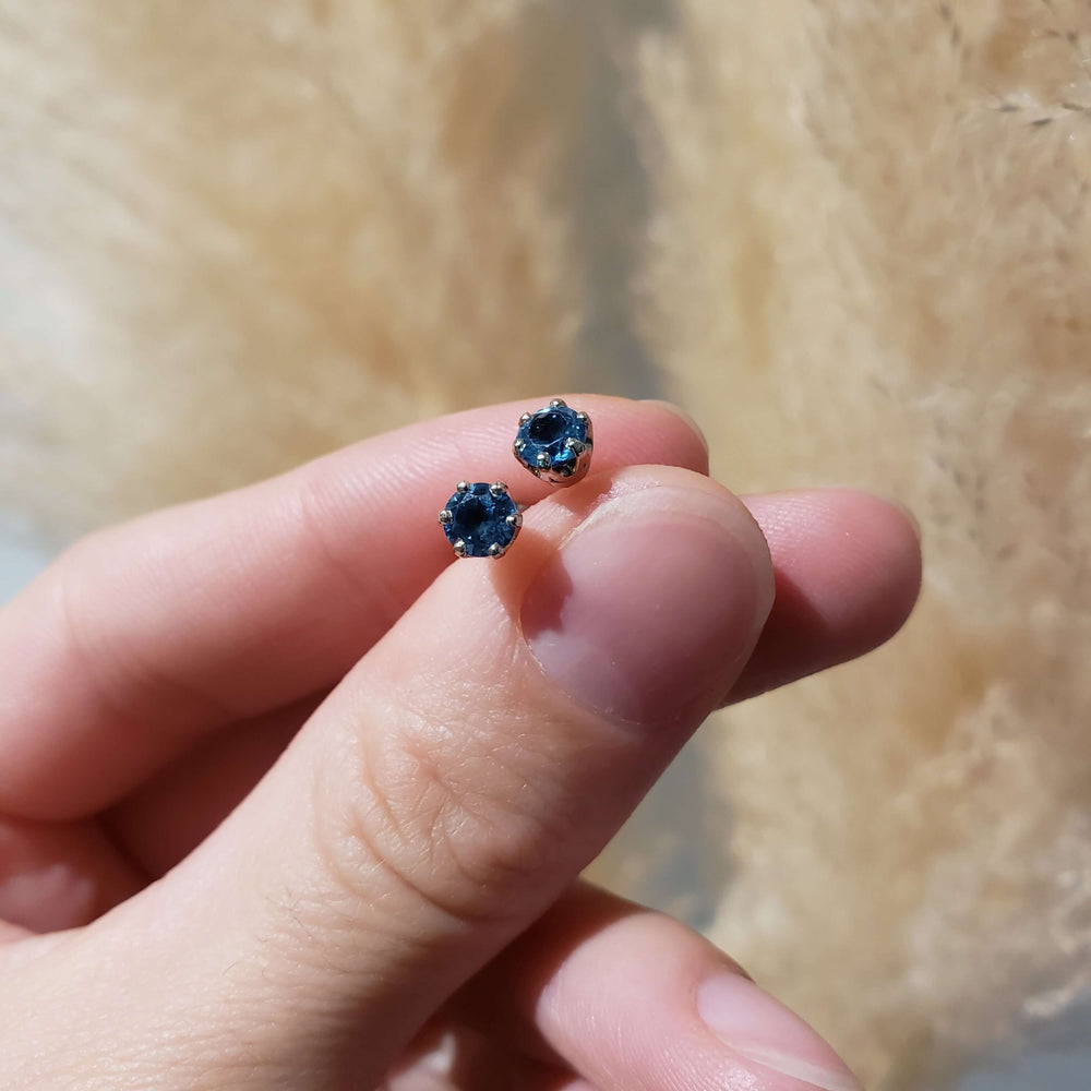 Hand holding a pair of Swiss blue topaz six-prong stud earrings