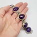 Hand holding vintage sterling silver bracelet with large amethyst cabochons