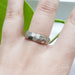 Hand wearing a 14kt white gold wedding ring with rough hand carved faceted design