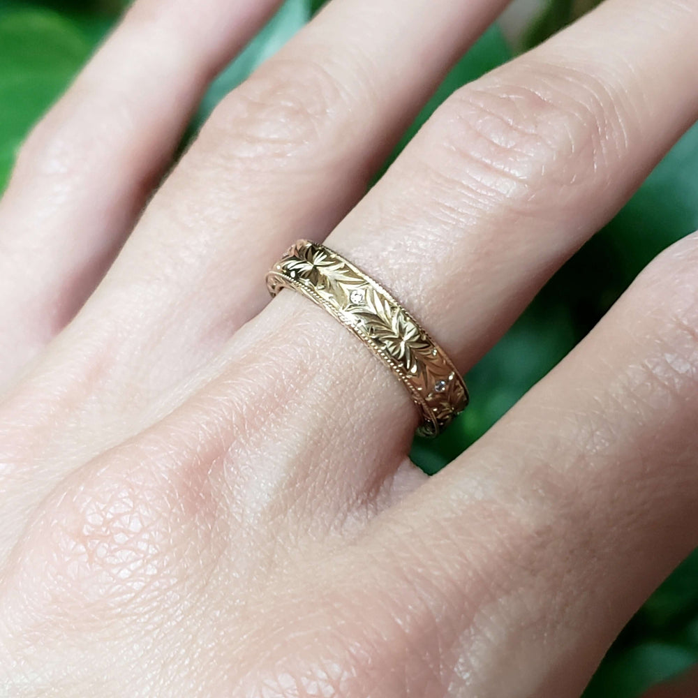 Hand wearing engraved 14kt yellow gold wedding ring with Canadian diamonds and floral design