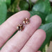 Hand holding round smoky quartz stud earrings in yellow gold