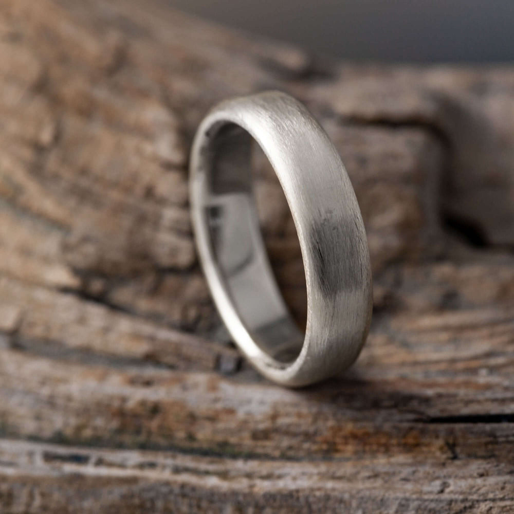 Handcrafted 14k white gold flat wedding ring with brushed texture on wood