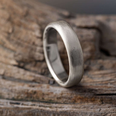 Handcrafted 14k white gold flat wedding ring with brushed texture on wood