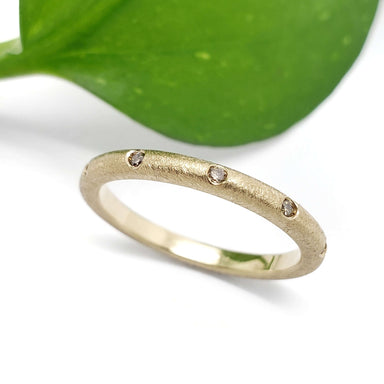 Handcrafted 14k yellow gold band with champagne diamonds, shown with a green leaf