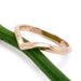 Handcrafted 14kt rose gold chevron wedding ring displayed on a green stem