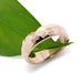 Handcrafted 14kt rose gold hammered wedding ring resting on a green leaf