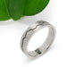 Handcrafted 14kt white gold mountain range ring with brushed texture, shown near a green leaf