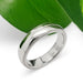 Handcrafted 14kt white gold wedding ring with millgrain detail beside green leaf