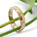 Handcrafted 14kt yellow gold bark texture wedding ring displayed with green stems