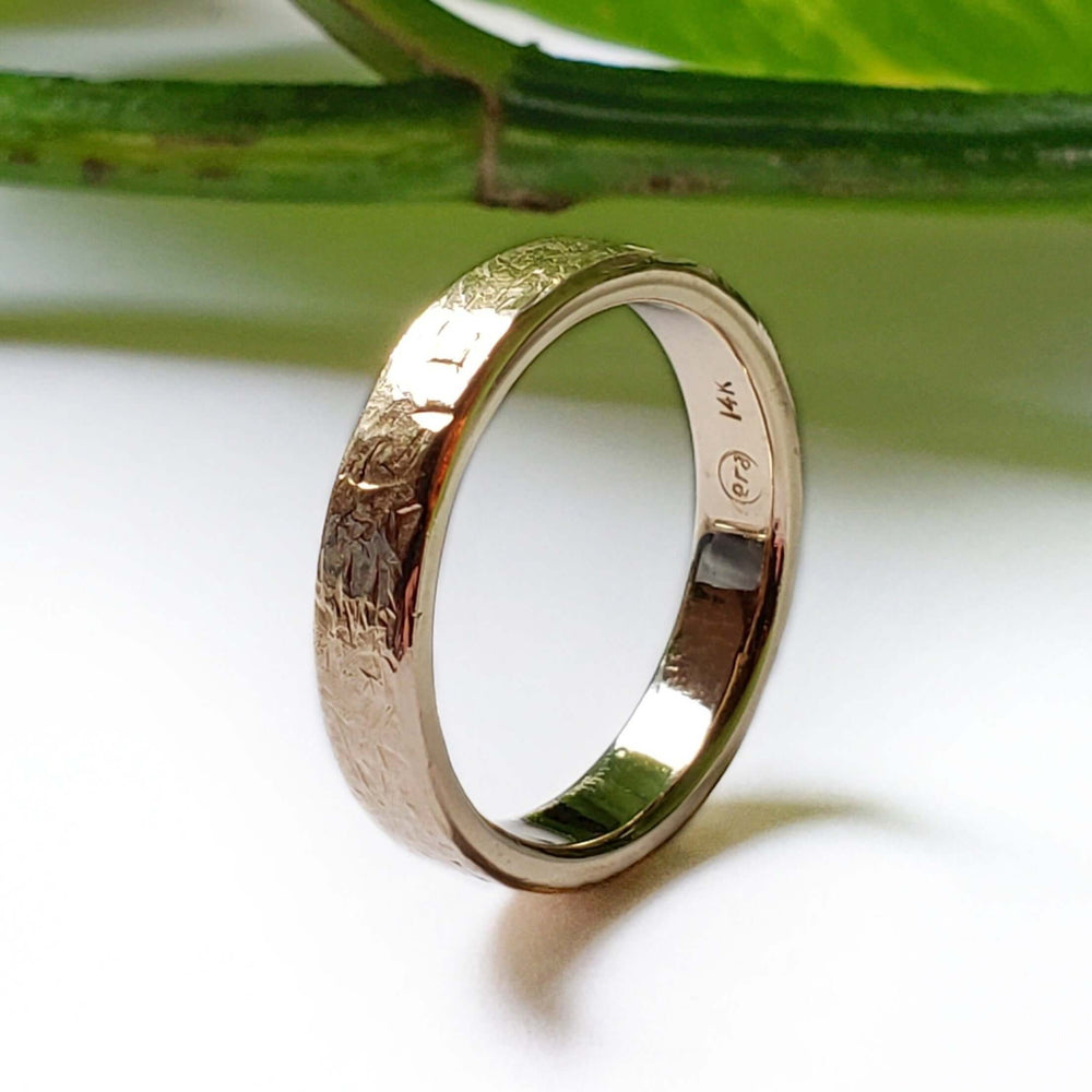 Handcrafted 14kt yellow gold textured wedding ring shown upright with hallmark visible